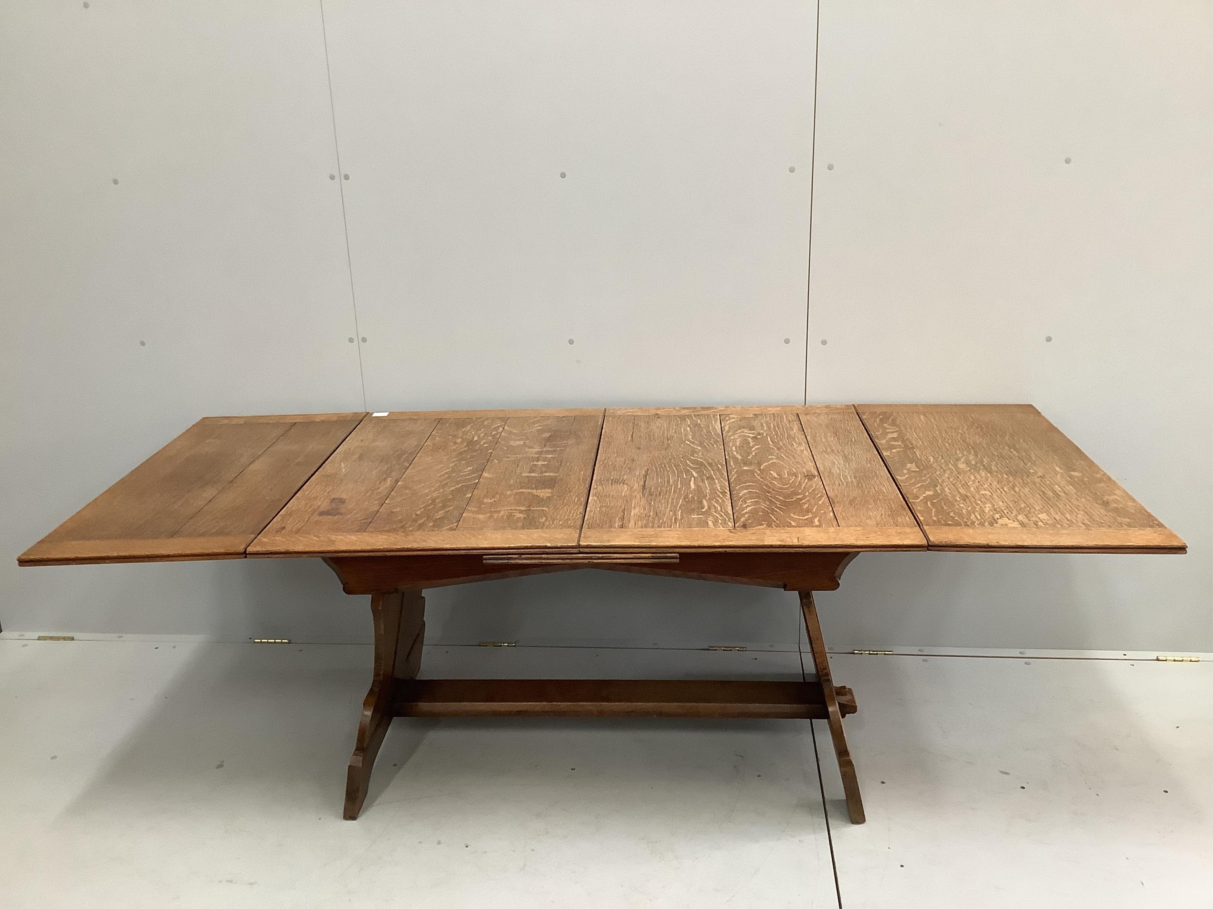 An oak draw leaf dining table, the shaped end standards united by flat stretcher, width 130cm, depth 91cm, height 72cm. Condition - fair